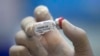 FILE - A lab technician holds a bottle containing results for a COVID-19 vaccine at a testing center run by Chulalongkorn University in Saraburi Province, north of Bangkok, Thailand, May 23, 2020.