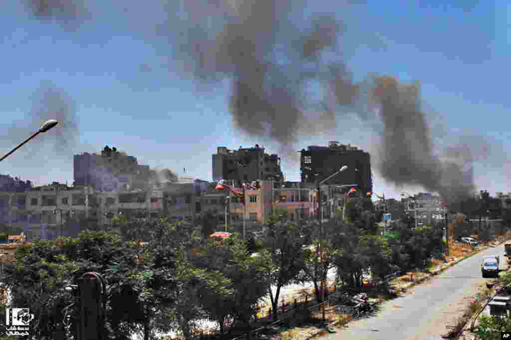 This citizen journalism image provided by Lens Young Homsi shows black smoke rising from buildings damaged by Syrian government airstrikes and shelling in Homs, Syria, July 7, 2013.
