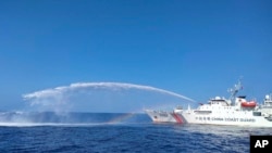 Sebuah kapal Penjaga Pantai China, kanan, menggunakan meriam air saat mendekati wilayah sengketa, Beting Scarborough di Laut China Selatan, 9 Desember 2023. (Foto: via AP)