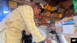 Abba Usman sells granulated sugar at his shop inside a market in Abuja, Nigeria on Oct. 27, 2023. The same 50-kilogram bag of sugar that Usman bought a week ago for $66 now costs $81. As prices rise, his customers are dwindling. (AP Photo/Chinedu Asadu)