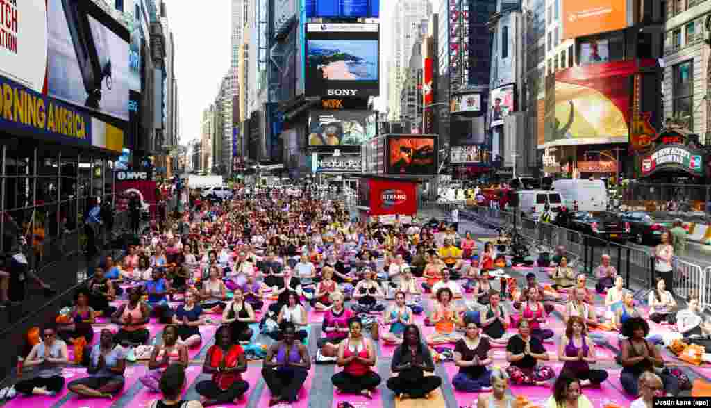 People participate in a group yoga class in Times Square as part of the 14th annual 'Solstice in Times Square: Mind Over Madness Yoga' to mark the summer solstice in New York.