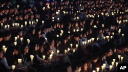 FILE – High school students in Ansan, South Korea, hold candles at a ceremony honoring victims of the Sewol ferry disaster two years earlier off the country’s southern coast.