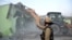 FILE - A police officer gestures as a bulldozer demolishes a property during a government demolition drive in Haldwani in the northern state of Uttarakhand, India, on Feb. 8, 2024.