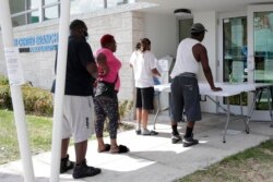 Restaurant worker Glen Pile, left, waits in line to get an unemployment form at a Miami-Dade County library during the coronavirus pandemic in Miami, April 8, 2020.