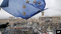 FILE - A supporter waves a European Union flag from a building top in Kyiv, Nov. 29, 2013.