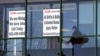FILE - A woman walks past the signs of an employment agency, in Manchester, N.H., March 2, 2021.