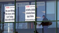 FILE - A woman walks past the signs of an employment agency, in Manchester, N.H., March 2, 2021.