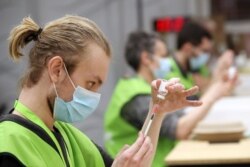 Medical workers prepare doses of Oxford/AstraZeneca's COVID-19 vaccine at a vaccination center in Antwerp, Belgium, March 18, 2021.
