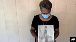Belvin Jefferson White poses with a portrait of her father Saymon Jefferson at Saymon's home in Baton Rouge, Louisiana, May 18, 2020. Belvin recently lost both her father and her uncle, Willie Lee Jefferson, to COVID-19. 
