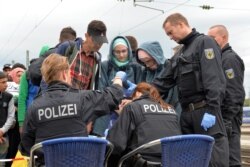 FILE - German policemen register refugees at the rail station in Freilassing, southern Germany, Sept. 14, 2015, before they take them away in busses.