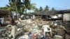 FILE - Tsunami survivors stand amid the ruins of a collapsed house in Pamadura, South of Colombo, Sri Lanka, Thursday, Dec. 30, 2004.