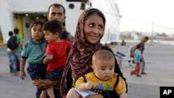 A family from Afghanistan arrives from the northeastern Greek island of Lesbos to the Athens' port of Piraeus on Monday, Sept. 7, 2015.