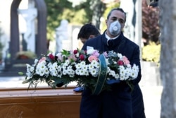 Cemetery workers and funeral agency workers in protective masks transport a coffin of a person who died from coronavirus disease (COVID-19), into a cemetery in Bergamo, Italy March 16, 2020.
