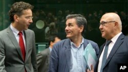 FILE - Greek Finance Minister Euclid Tsakalotos, center, speaks with Dutch Finance Minister Jeroen Dijsselbloem, left, and French Finance Minister Michel Sapin during a meeting of eurozone finance ministers in Brussels, July 7, 2015. 