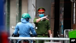 A police officer talks to a woman at the barricaded entrance of an alley where one of its residents is suspected to have COVID-19 in Hanoi, Vietnam, July 29, 2020.