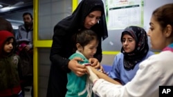 A Syrian girl cries after receiving the measles vaccine from UNICEF nurses Nadine Houjairi (2nd R), and Genivieve Bashalani (R) at the U.N. refugee agency's registration center in Zahleh, in Lebanon's Bekaa Valley, Dec. 18, 2013.
