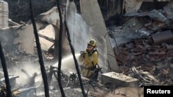 লস অ্যাঞ্জেলেসের প্যাসিফিক প্যালিসেডস মহল্লায় প্যালিসেড দাবানলে পুড়ে যাওয়া একটি বাড়িতে পানি ছিটাচ্ছেন এক দমকলকর্মী। ১০ জানুয়ারি, ২০২৫।