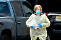 FILE - A health worker prepares to administer a saliva-based COVID-19 test kit, at a testing site in Edison, New Jersey, April 15, 2020.