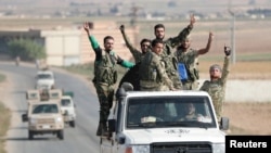 Rebeldes sirios apoyados por Turquía saludan el 22 de octubre de 2019 cerca de la frontera entre Siria y Turquía.