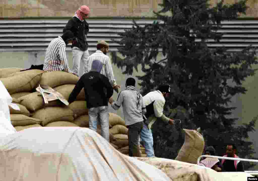 Members of the Free Syrian Army and men from the northern Syrian town of Ras al-Ain unload wheat from trucks, as seen from the Turkish border town of Ceylanpinar, Sanliurfa province, November 26, 2012. 