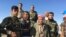 Elder Peshmerga fighter and now a volunteer, Omar Mirhan stands with his fellow Peshmerga on a hill overlooking the area of Makhmour which the Peshmerga won back from Islamic State in 2014, March 8, 2016. (S. Behn/VOA)