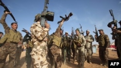 Iraqi fighters from the Shiite Muslim Al-Abbas popular mobilisation unit hold up their weapons in the area surrounding the village of Nukhayb in the embattled Anbar province west of the capital Baghdad, May 19, 2015.