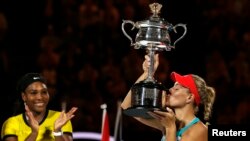 Angelique Kerber mencium piala kemenangannya, setelah mengalahkan petenis AS Serena Williams dalam Kejuaraan Tenis Australia Terbuka di Melbourne Park, Australia (30/1). 