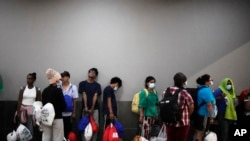 Những người di cư, chủ yếu từ các nước Châu Á, đang chờ được đưa đến khách sạn sau khi đến Panama City.