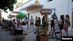 FILE - People sit at a bar near Barceloneta beach, after Catalonia's regional authorities and the city council announced restrictions to contain the spread of the coronavirus disease, in Barcelona, Spain, July 19, 2020. 