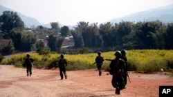 FILE - Myanmar army soldiers carrying weapons patrol on a road as part of operations against ethnic rebels, in Kokang, northeastern Shan State, more than 800 kilometers (500 miles) northeast of Yangon, Myanmar.