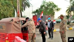 Iraqi security forces search people heading to Tahrir Square where ongoing anti-government protests are taking place in Baghdad, Dec. 8, 2019.