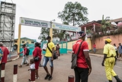 FILE - Some people wear masks as they walk by the entrance to the Yaounde General Hospital in Yaounde on March 6, 2020. Cameroon has been hit harder by the coronavirus than any other country in Central Africa.