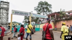 FILE - Some people wear masks as they walk by the entrance to the Yaounde General Hospital in Yaounde on March 6, 2020. Cameroon has been hit harder by the coronavirus than any other country in Central Africa.