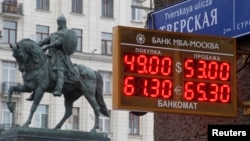 A board showing currency exchange rates, in front of a monument to Prince Yury Dolgoruky, who founded Moscow in 1147, in the capital Moscow, Dec. 1, 2014.