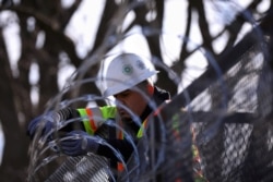 A worker installs razor wire on fencing in front of the U.S. Capitol as an extra security measure in Washington, Jan. 18, 2021.