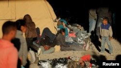 FILE - A young boy walks near other migrants lying on the ground inside an enclosure, where they are being held by U.S. Customs and Border Protection, after crossing the U.S.-Mexico border illegally and turning themselves in to request asylum, in El Paso, Texas, March 29, 2019.