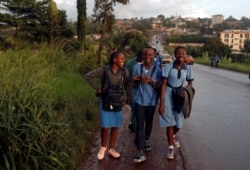 FILE - Schoolchildren smile as they walk out of school, on the outskirts of Yaounde, Cameroon, Oct. 9, 2018.