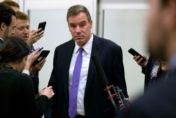 FILE - Sen. Mark Warner, D-Va., talks to reporters on Capitol Hill in Washington, Jan. 28, 2020.