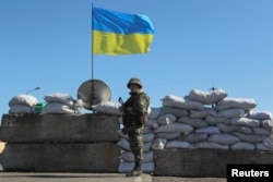 FILE - A Ukrainian serviceman stands guard at a checkpoint near the town of Armyansk in Kherson region adjacent to Crimea, March 21, 2014.