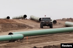 FILE - A vehicle drives next to a series of pipes at a Dakota Access construction site near the town of Cannon Ball, North Dakota, Oct. 30, 2016.