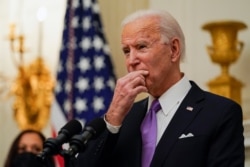 FILE - President Joe Biden pauses as he speaks about the coronavirus, accompanied by Vice President Kamala Harris, in the State Dining Room of the White House, Jan. 21, 2021, in Washington.