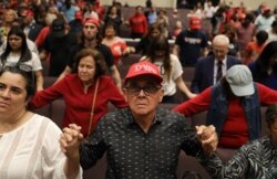 FILE - People pray together during the 'Evangelicals for Trump' campaign event held at the King Jesus International Ministry as they await the arrival of President Donald Trump on Jan. 3, 2020 in Miami, Florida.
