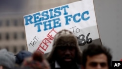 A protester holds a sign that reads "Resist the FCC. Text: INTERNET To: 52886" at the Federal Communications Commission (FCC), in Washington, Dec. 14, 2017.
