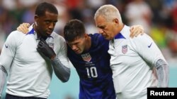 Punggawa Timnas AS Christian Pulisic harus dipapah setelah bertabrakan dengan pemain Iran Alireza Beiranvand dalam pertandingan Grup B Piala Dunia 2022 antara Iran melawan AS di Stadion Al Thumama di Doha, Qatar, pada 29 November 2022. (Foto: Reuters/Kai Pfaffenbach)