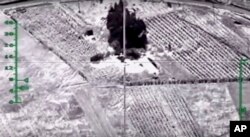 In this photo made from video footage provided by the Russian Defense Ministry on Dec. 9, 2015, a target is hit during an airstrike. Russia has unleashed another barrage of airstrikes against targets in Syria, including the first combat launch of a new cruise missile from a Russian submarine in the Mediterranean Sea.
