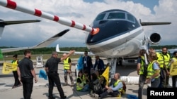 Para aktivis lingkungan dari Greenpeace, Stay Grounded, Extinction Rebellion, Scientist Rebellion dan organisasi lainnya berdemo memprotes penggunaan jet pribadi pada konvensi dirgantara EBACE di Jenewa, Swiss, 23 Mei 2023. (Foto: Greenpeace via Reuters)