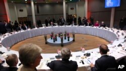 British Prime Minister Theresa May, foreground, walks by as EU leaders sit for a dinner meeting at an EU summit in Brussels, May 28, 2019.
