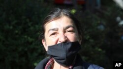 FILE - In this May 24, 2020, photo, Muyesser Yildiz wears a face mask to protect against the coronavirus as she visits a public garden, in Ankara, Turkey.