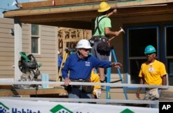 FILE - Former President Jimmy Carter helps cut wood for home construction at a Habitat for Humanity construction site in the Globeville neighborhood of Denver, Wednesday Oct. 9, 2013. (AP Photo/Brennan Linsley)