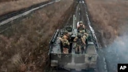 En esta fotografía tomada de un vídeo publicado por el Servicio de Prensa del Ministerio de Defensa ruso el sábado 13 de abril de 2024, soldados rusos viajan en su vehículo blindado para tomar posiciones y disparar hacia posiciones ucranianas en un lugar no revelado en Ucrania. 
